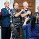 President Donald Trump stands in the rain with members of Bikers for Trump and supporters as they say the Pledge of Allegiance, Saturday, Aug. 11, 2018, at the clubhouse of Trump National Golf Club in Bedminster, N.J.